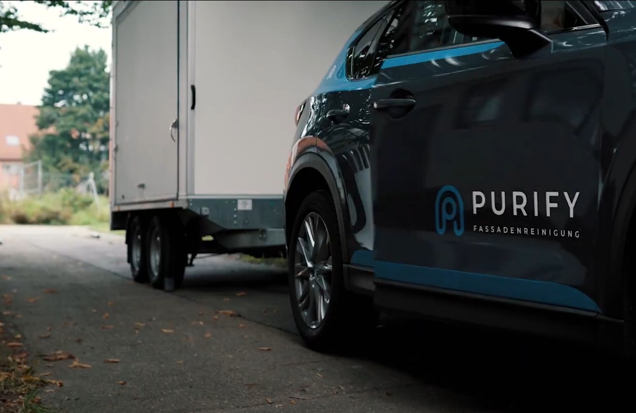 Ein mit dem Purify-Logo beschriftetes Einsatzfahrzeug steht in Reutlingen vor einem Anhänger – bereit für die nächste Fassadenreinigung vor Ort.