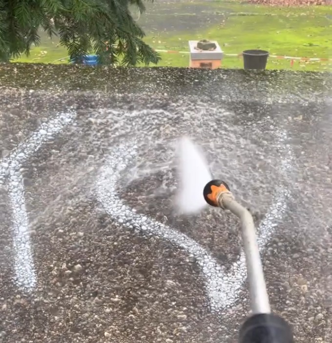 Graffiti auf Betonwand wird mit Wasserstrahl abgespült.