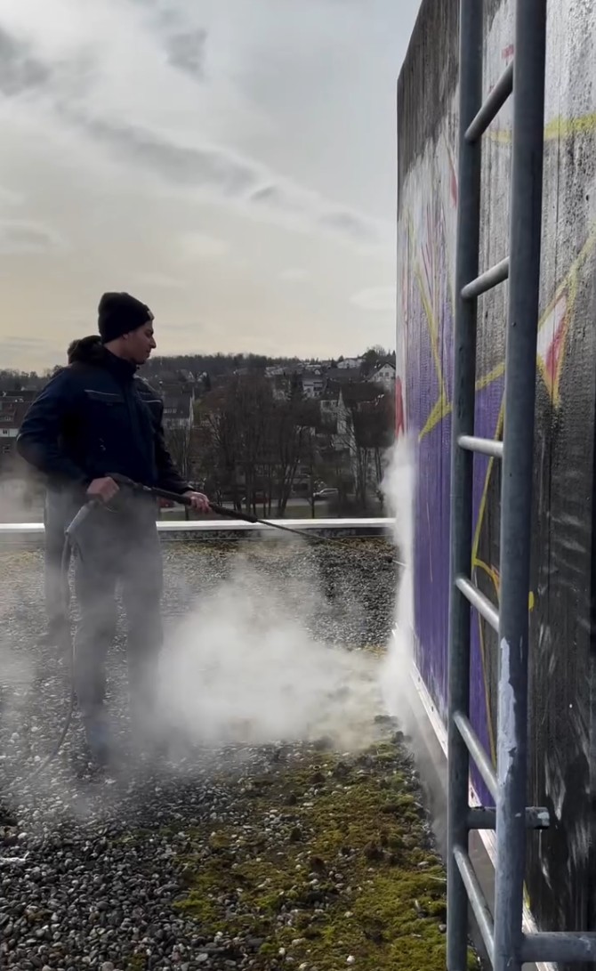 Mitarbeiter von Purify entfernt Graffiti mit Niederdrucktechnik an einer Wand in Heidelberg.