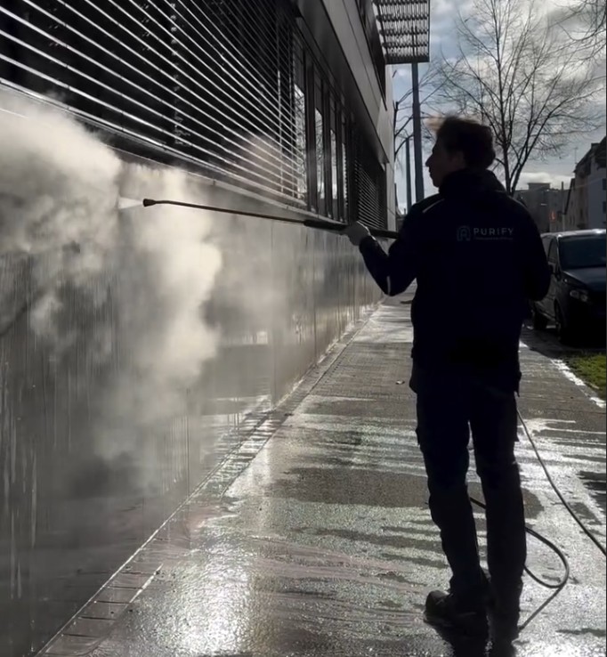Purify-Mitarbeiter entfernt Graffiti-Schatten von Betonfassade.