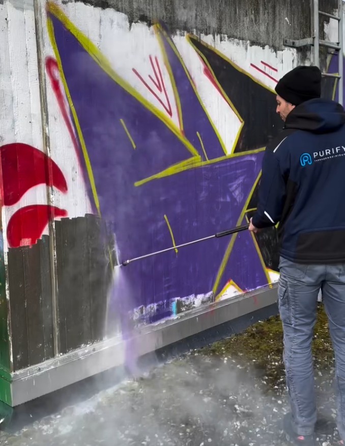Graffiti auf Wand in Stuttgart wird von einem Purify-Mitarbeiter mit Niederdruckreiniger entfernt.