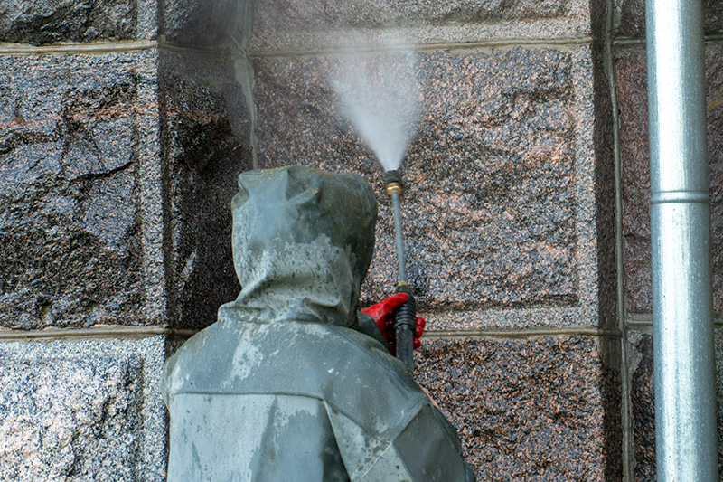 Fachgerechte Reinigung einer Natursteinfassade aus Granit mit Hochdruck.
