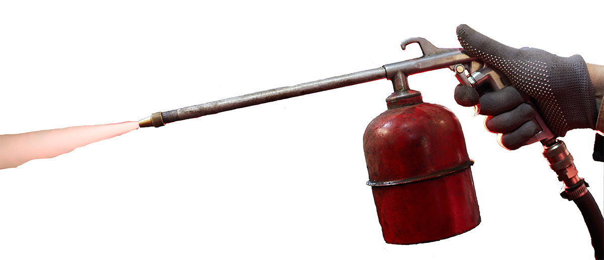 Sandstrahlpistole mit rotem Druckbehälter in der Hand eines Arbeiters im Einsatz.