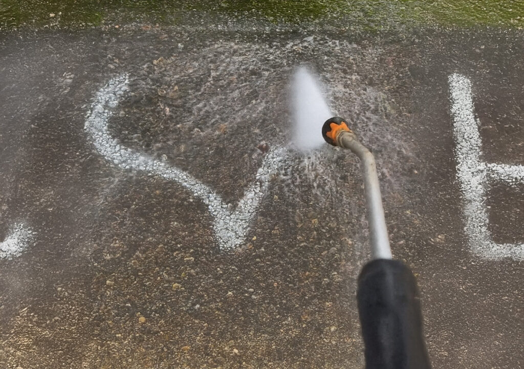 Ein Facharbeiter reinigt eine Betonfläche mit Hochdruck, um Graffiti zu entfernen.