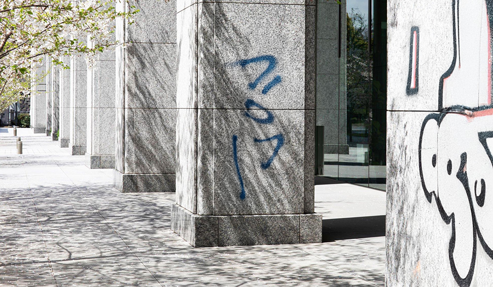 Graffiti auf einer Granitfassade im öffentlichen Raum.