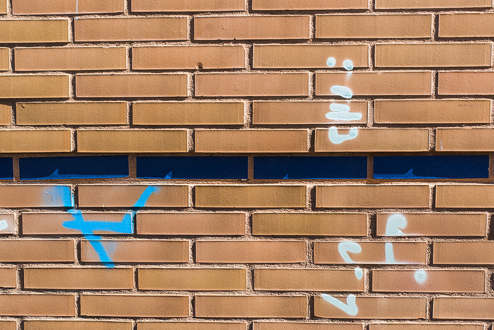 Graffiti auf einer Klinkerfassade mit blauer und weißer Sprühfarbe
