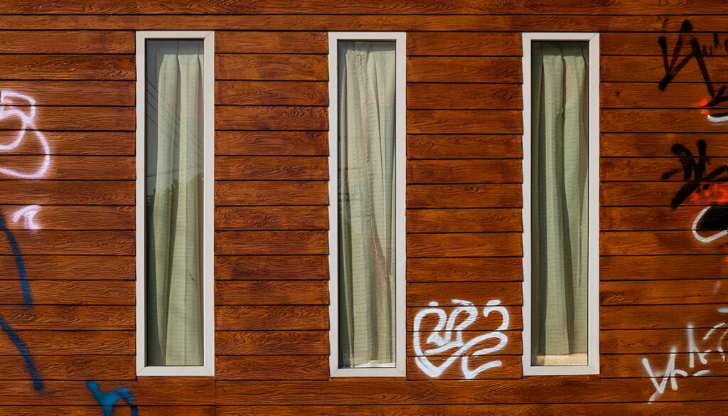 Holzfassade mit Graffiti vor der Reinigung – Beispiel für die Wirkung von Graffitischutz auf Holz