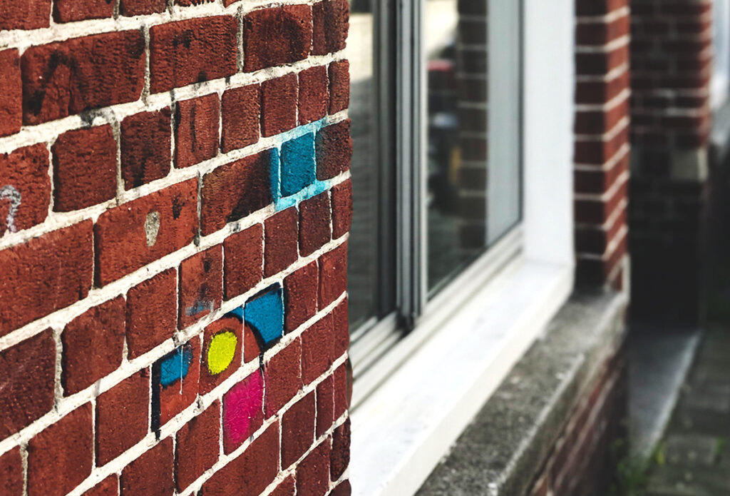 Klinkerfassade mit buntem Graffiti – Beispiel für ungeschützte, offenporige Oberfläche vor der Reinigung.