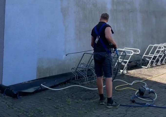 Facharbeiter reinigt eine verschmutzte Kunstharzputz-Fassade mit Niederdrucktechnik.