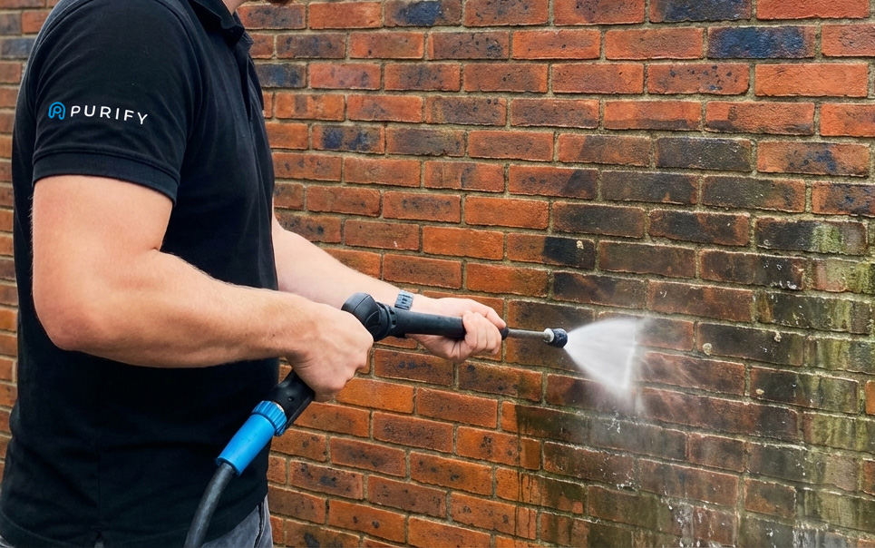 Backsteinfassade reinigen mit Niederdrucktechnik Professionelle Reinigung einer Backsteinfassade mit Niederdrucktechnik, sichtbar sind Schmutz- und Algenbeläge sowie der Reinigungsstrahl.