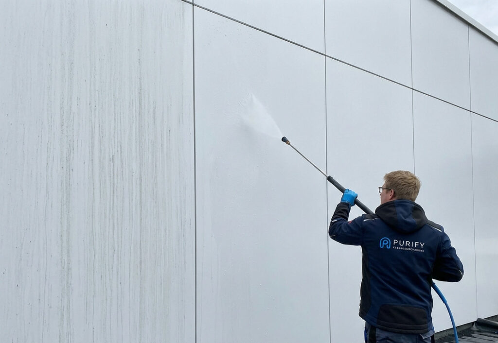 Pulverbeschichtete Fassade reinigen mit professioneller Niederdrucktechnik Techniker von Purify reinigt eine pulverbeschichtete Fassade schonend mit Niederdrucktechnik, sichtbarer Vorher-Nachher-Effekt auf moderner Aluminiumfassade.