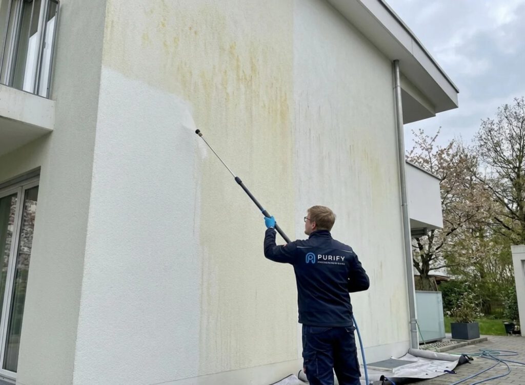 Blütenflecken entfernen mit professioneller Fassadenreinigung Techniker entfernt Blütenflecken an einer hellen Fassade mit schonender Niederdrucktechnik