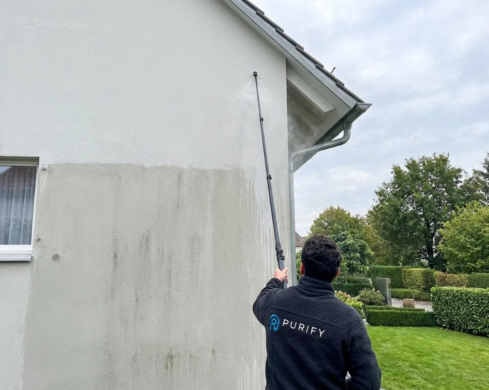 Was beinhaltet Fassadenreinigung? Professionelle Reinigung im Einsatz Mitarbeiter reinigt Hausfassade mit Teleskoplanze und Niederdrucktechnik – Beispiel für professionelle Fassadenreinigung