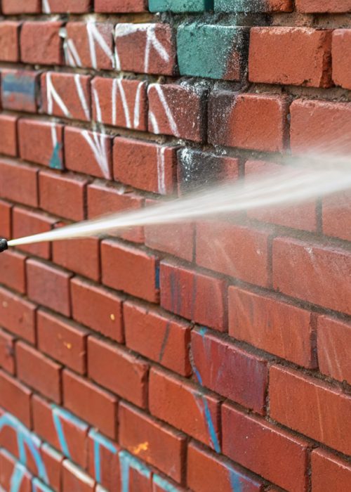 Fassadenreinigung in Heilbronn: Professionelle Graffitientfernung mit Hochdrucklanze auf roter Klinkerfassade.