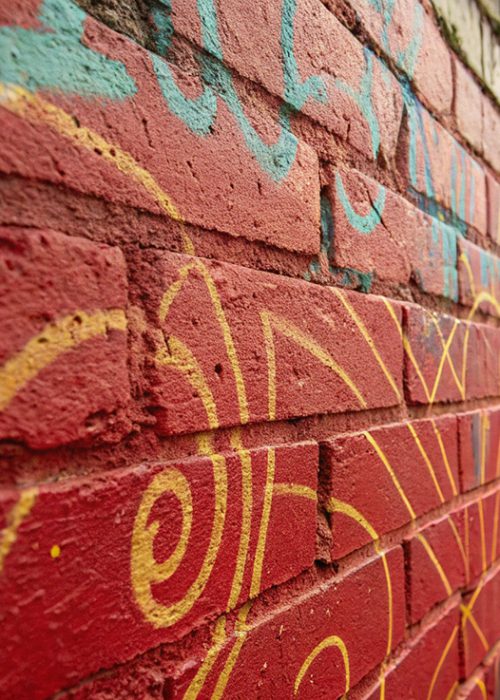 Rote Backsteinwand in Mannheim mit Graffiti vor der Reinigung.